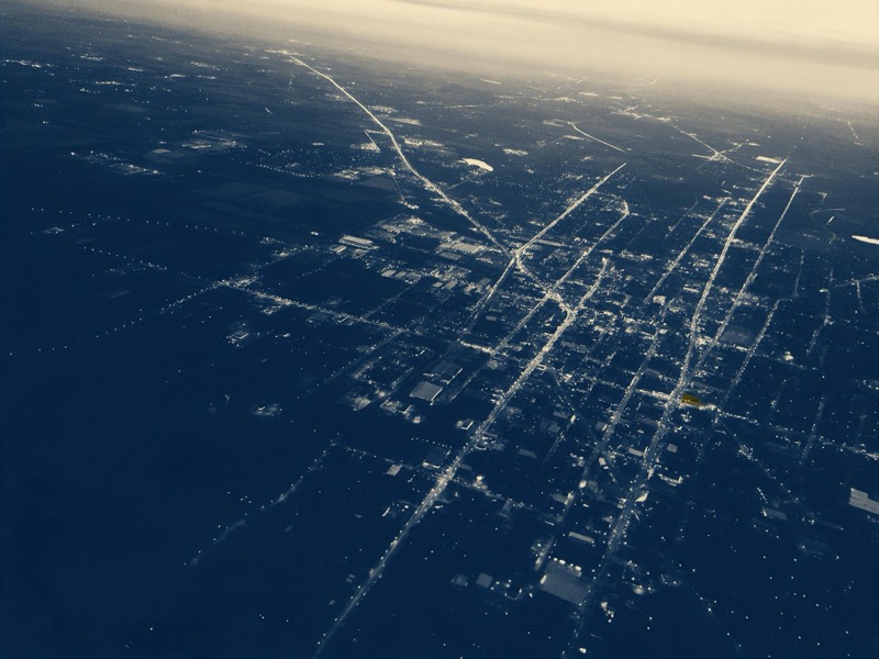 a city seen from the air at dusk, streets as lines of light